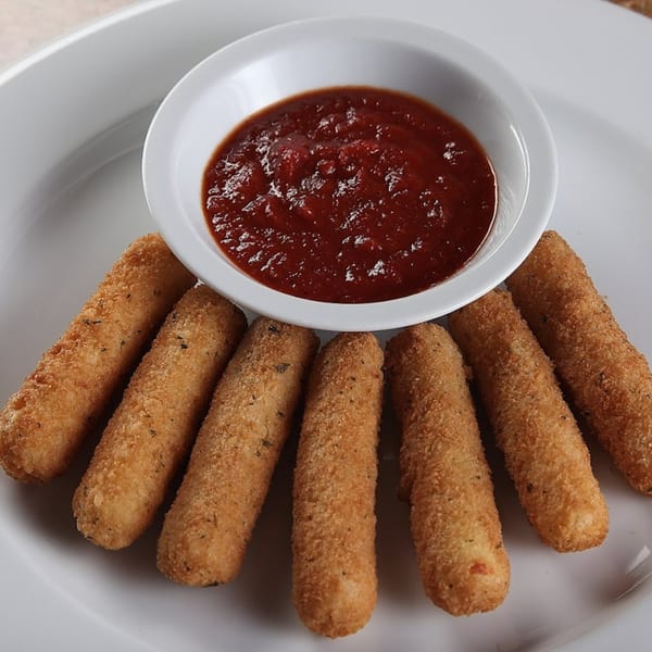 Seven golden-brown mozzarella sticks arranged around a white bowl of marinara sauce on a white plate.