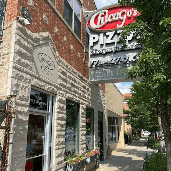 Exterior of Chicago's Pizza restaurant with a red sign, stone facade, and sidewalk with trees.