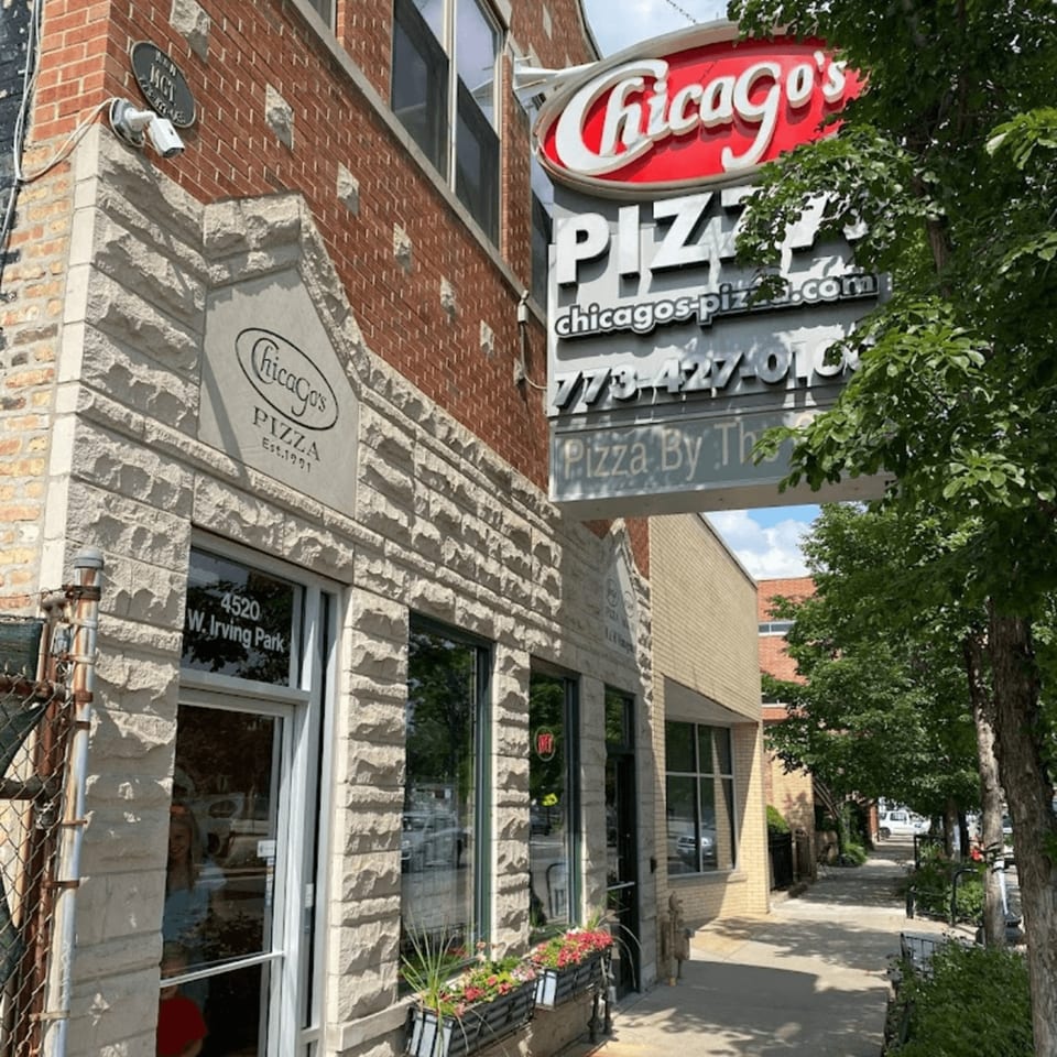 Exterior of Chicago's Pizza restaurant with a red sign, stone facade, and sidewalk with trees.