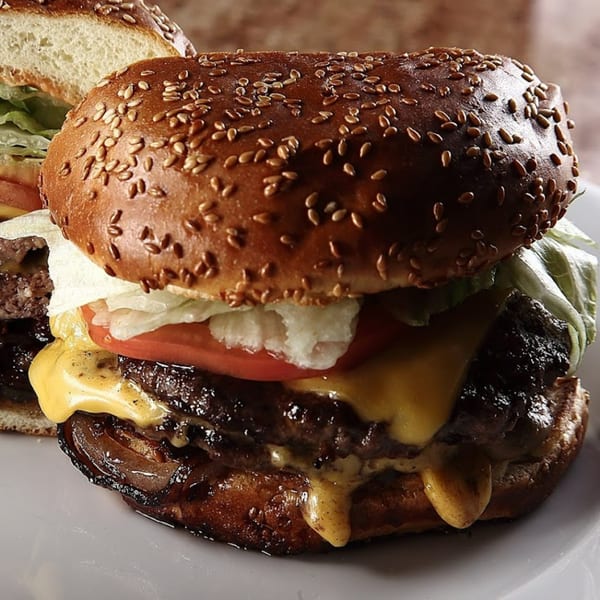 A Chicago's Pizza burger with melted cheese, lettuce, tomato, and caramelized onions on a sesame bun.