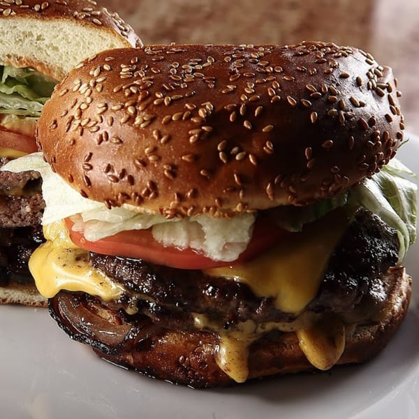 Close-up of a Chicago's Pizza burger with melted cheese, lettuce, tomato, and caramelized onions.
