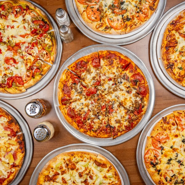 Overhead view of six Chicago's Pizza pizzas with various toppings, including pepperoni, olives, and pineapple.