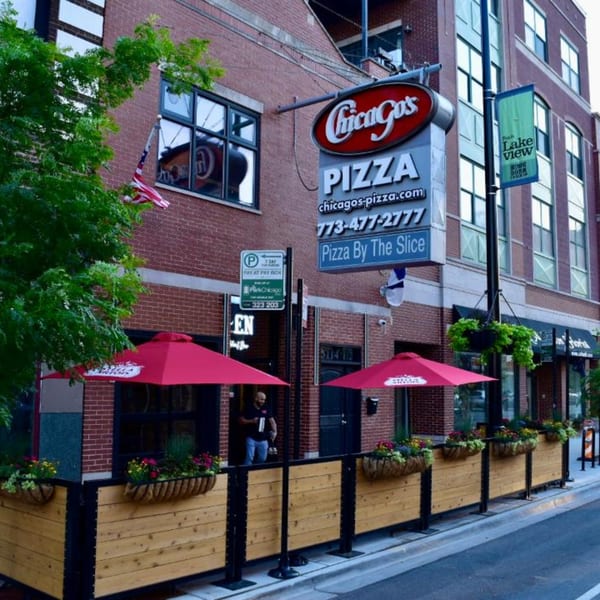 Chicago's Pizza storefront with a large sign, outdoor patio seating with red umbrellas, and flower boxes.